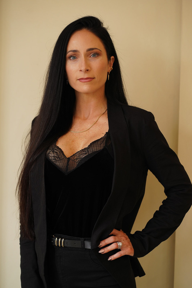 A professional blue-eyed woman with long black hair and a black blazer